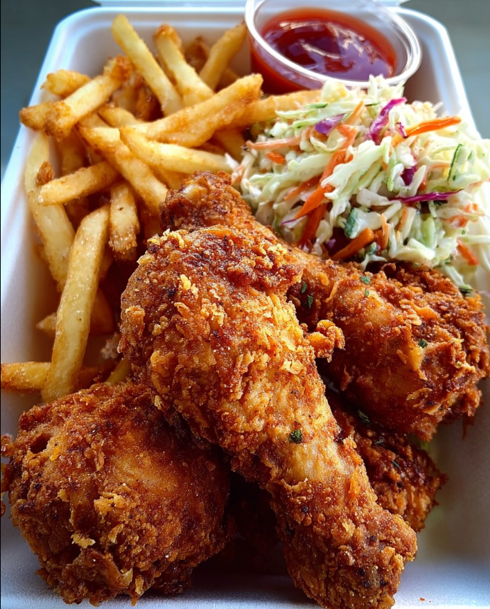 Box con pollo fritto croccante, patatine fritte e insalata di cavolo.